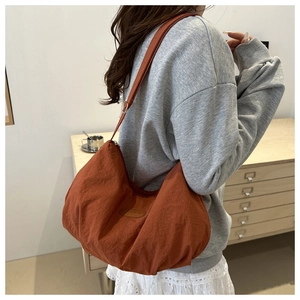 Detail of orange crescent bag made of textured nylon fabric with adjustable shoulder strap