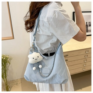 Borsa tote celeste con ciondolo a nuvola e tracolla a catena in un interno moderno