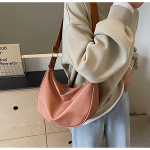 Detail of soft pink nylon crescent bag with adjustable dark brown shoulder strap and metal buckle