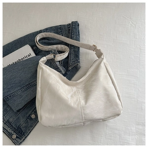 Detail shot of the white hobo tote bag featuring shiny wrinkled PU leather and gold rings