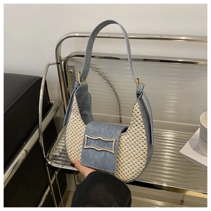 Detail of blue denim and woven straw crescent bag featuring a gold metal buckle