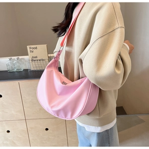 Close-up of pink nylon crescent bag with wide shoulder strap and silver metal zipper