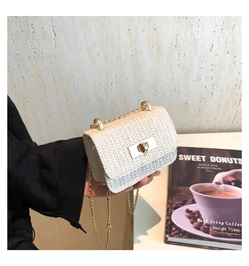 Detail of cream woven mini crossbody bag with golden chain and elegant metal twist lock