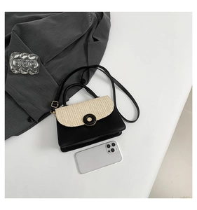Close-up of contrast-colored small crossbody bag with woven flap and phone for scale