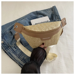 Detail of woven straw crossbody bag with leather trim and wide shoulder strap