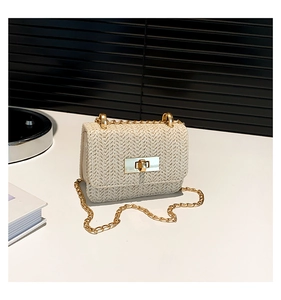 Detail view of cream straw mini bag featuring V-shaped weave and gold-tone turn lock