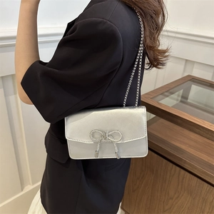Silver metallic crossbody bag with rhinestone bow and chain strap on female model