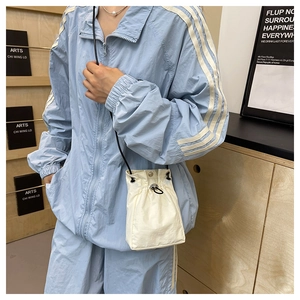 Close-up of white drawstring crossbody bag with pleated texture and black toggle cord