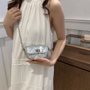 Silver quilted mini crossbody bag with chain strap shown on a model in a white dress