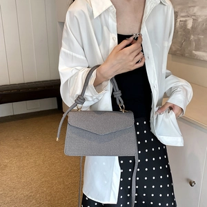 Gray textured crossbody bag with thick knotted handle and minimalist envelope design