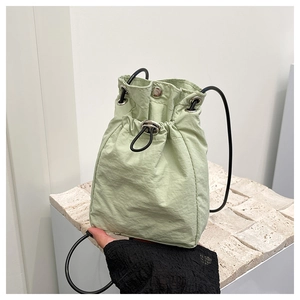 Detail of mint green nylon mini crossbody bag with drawstring closure and slim black strap