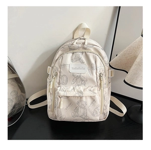 Detail view of cream backpack featuring bear pattern and durable multi-pocket design