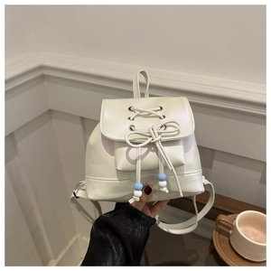 Détail d'un mini sac à dos crème avec un design à lacets décoratif et des nœuds