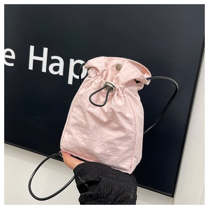Detail of pink nylon drawstring bag featuring metal snap closure and thin black strap