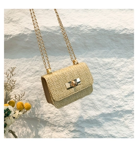 Close-up of beige woven straw crossbody bag with golden metal twist lock and V-pattern