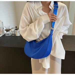 Detail of blue nylon crescent bag with adjustable strap in a lifestyle coffee shop setting