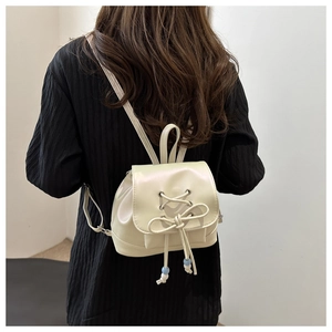 Détail du mini sac à dos en cuir PU crème avec nœud et perles sur le cordon