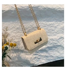 Detail of V-shaped straw weave pattern and gold metallic lock on a cream crossbody bag