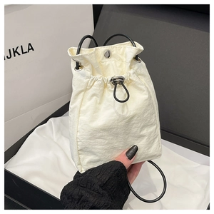 Detail of white nylon drawstring bucket bag with black handles and silver cord lock