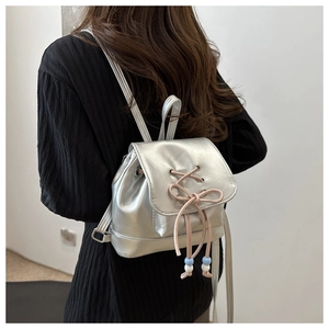 Mini sac à dos argenté avec nœud rose porté par un mannequin sur un haut noir