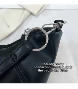 Detail of silver metal buckle and chain connection on a black leather croissant bag