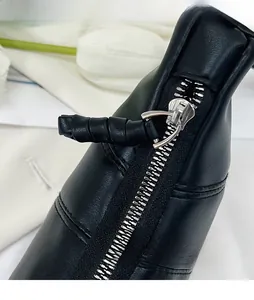 Detail of a black leather bag featuring a premium metal zipper and woven leather puller