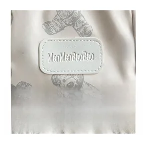Close-up of bear pattern fabric and MenMenBaoBao brand label on the lightweight backpack
