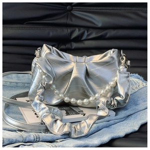 Detailed view of silver metallic bow bag with large pearl chain and ruffled strap detail