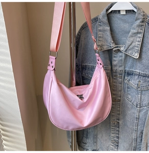 Detailed view of pink nylon crescent bag with wide strap and silver zipper closure