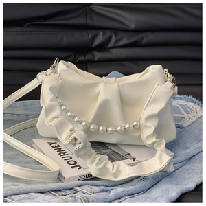 Detail of off-white ruched shoulder bag featuring a pearl chain and journey book prop