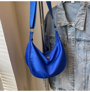 Detail view of the vibrant royal blue nylon crescent bag with wide fabric shoulder strap