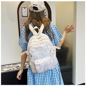Rear view of model wearing a beige backpack with bear prints and adjustable straps
