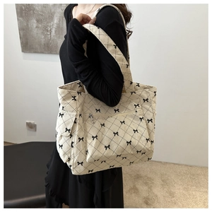 Detail of cream corduroy tote bag with black bow print and quilted texture