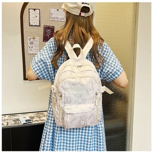 Detail of canvas backpack with cute cartoon bear prints and leather logo on front pocket