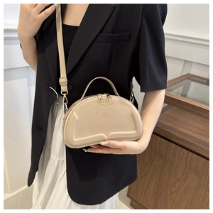 Detail of beige quilted half-moon bag featuring double zippers and refined gold hardware
