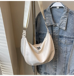 Detail view of cream nylon crescent bag with silver zipper and adjustable strap