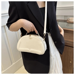 Detail of a chic cream-colored semi-circular crossbody bag with golden hardware and fashion logo