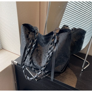 Detailed view of black embossed tote bag featuring woven leather handles and floral texture