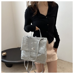 Détail du sac à bandoulière argenté plissé avec fermoir rotatif ovale élégant