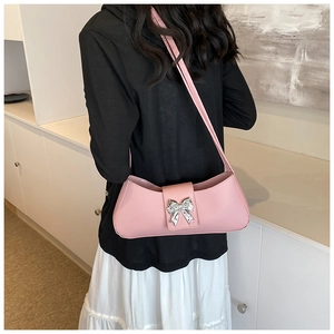 Vue portée d'un sac sous le bras en cuir rose brillant avec boucle papillon argentée