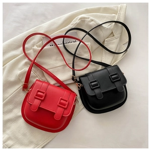 Detailed flat lay of red and black matte leather saddle bags with decorative buckles