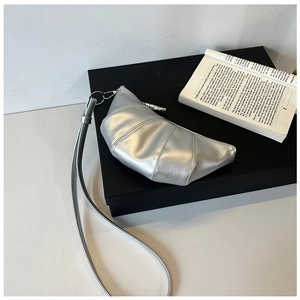 Detailed view of silver croissant bag featuring classic stitching and metallic finish