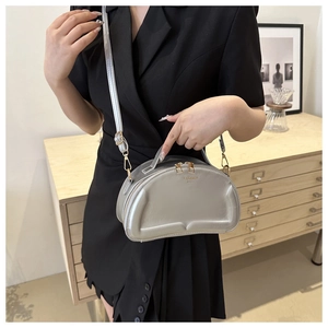 Close-up of a silver crescent bag with Fashion Bags print and golden zipper detail