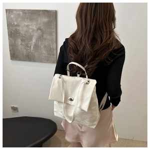 Détail d'un sac à bandoulière blanc à texture plissée et fermoir pivotant en métal poli
