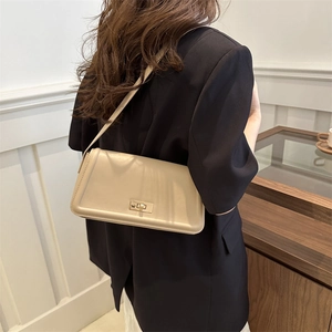 Borsa a spalla beige in pelle verniciata con chiusura girevole dorata su modella