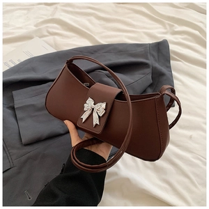 Détail d'un sac baguette marron foncé avec une boucle papillon en métal argenté