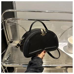 Detail of black matte leather crescent bag with gold zipper on a modern shelf display