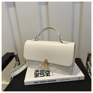Macro detail of white quilted texture and elegant gold metallic lock on a fashion handbag