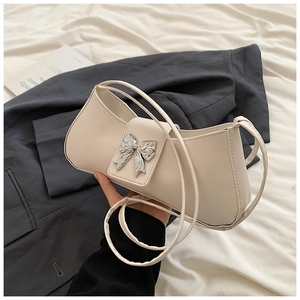 Détail d'un sac hobo en cuir PU beige avec boucle papillon argentée et fine bandoulière