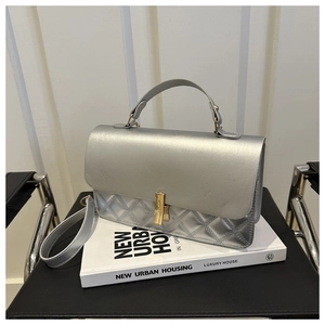 Detailed view of silver quilted crossbody bag with gold lock and metal chain handle